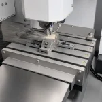 A CNC machine is processing a ceramic workpiece while coolant is sprayed over the cutting area to support precision machining.