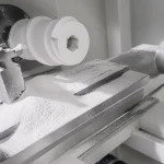 A white ceramic component is mounted in a machining setup for dry turning during precision ceramic component production.